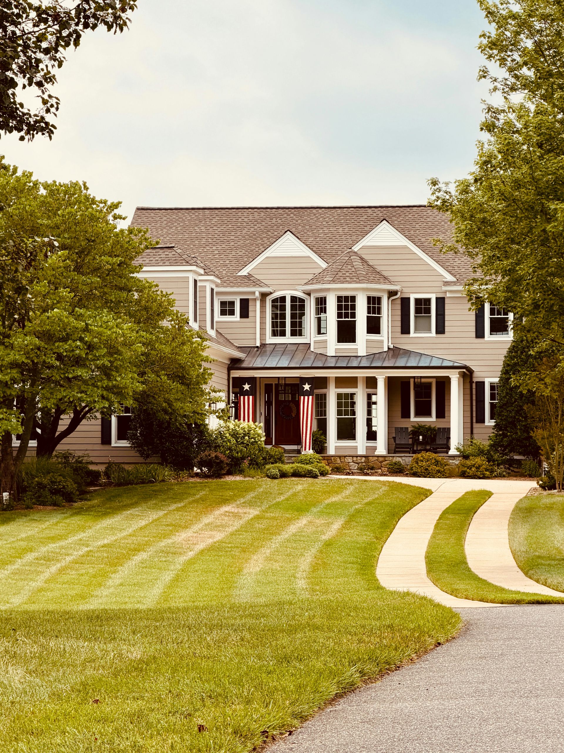 Large house with winding driveway and manicured lawn.