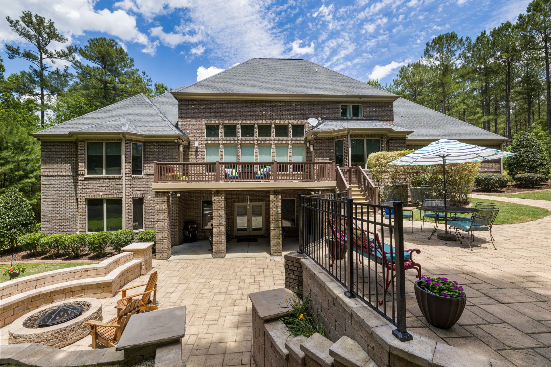 Luxury brick house featuring a large terrace, fire pit, and well-maintained garden.