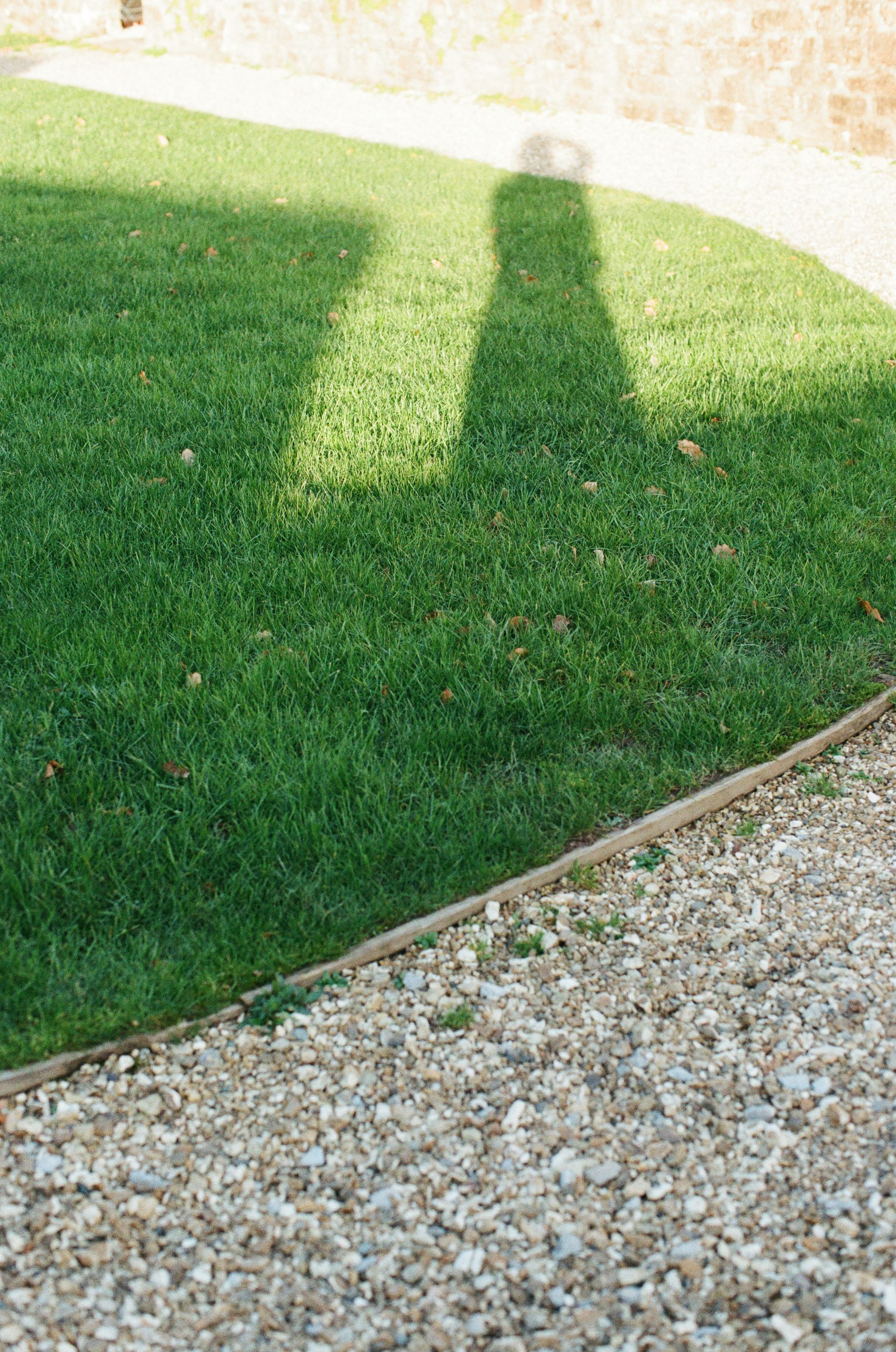Shadow of a person on a grassy lawn.